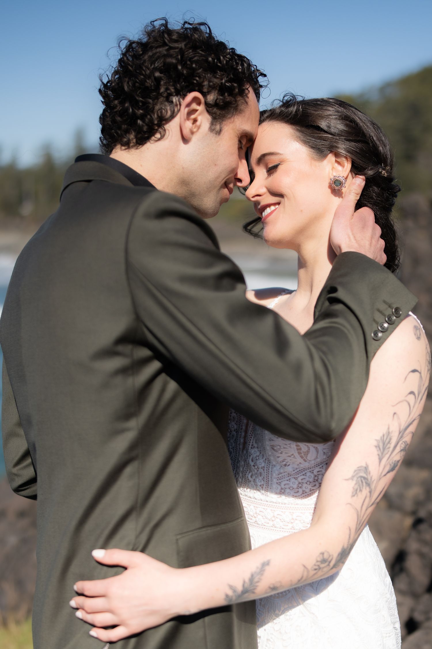 Intimate wedding moment captured against stunning coastal backdrop.