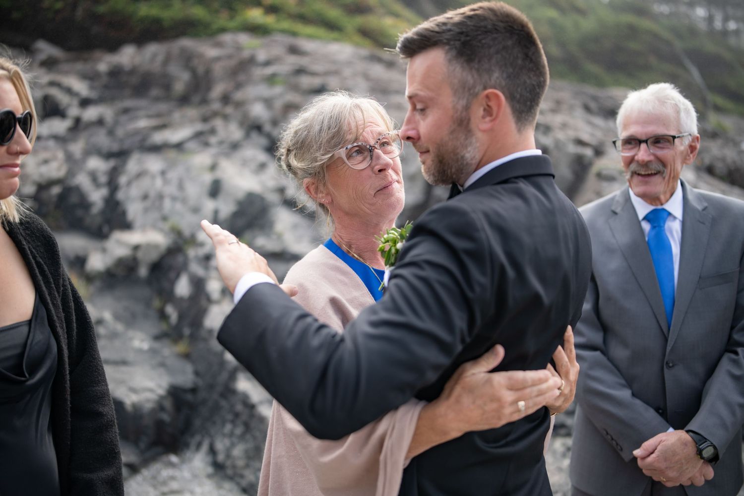 Intimate moment shared between wedding attendees with rocky coastal scenery.