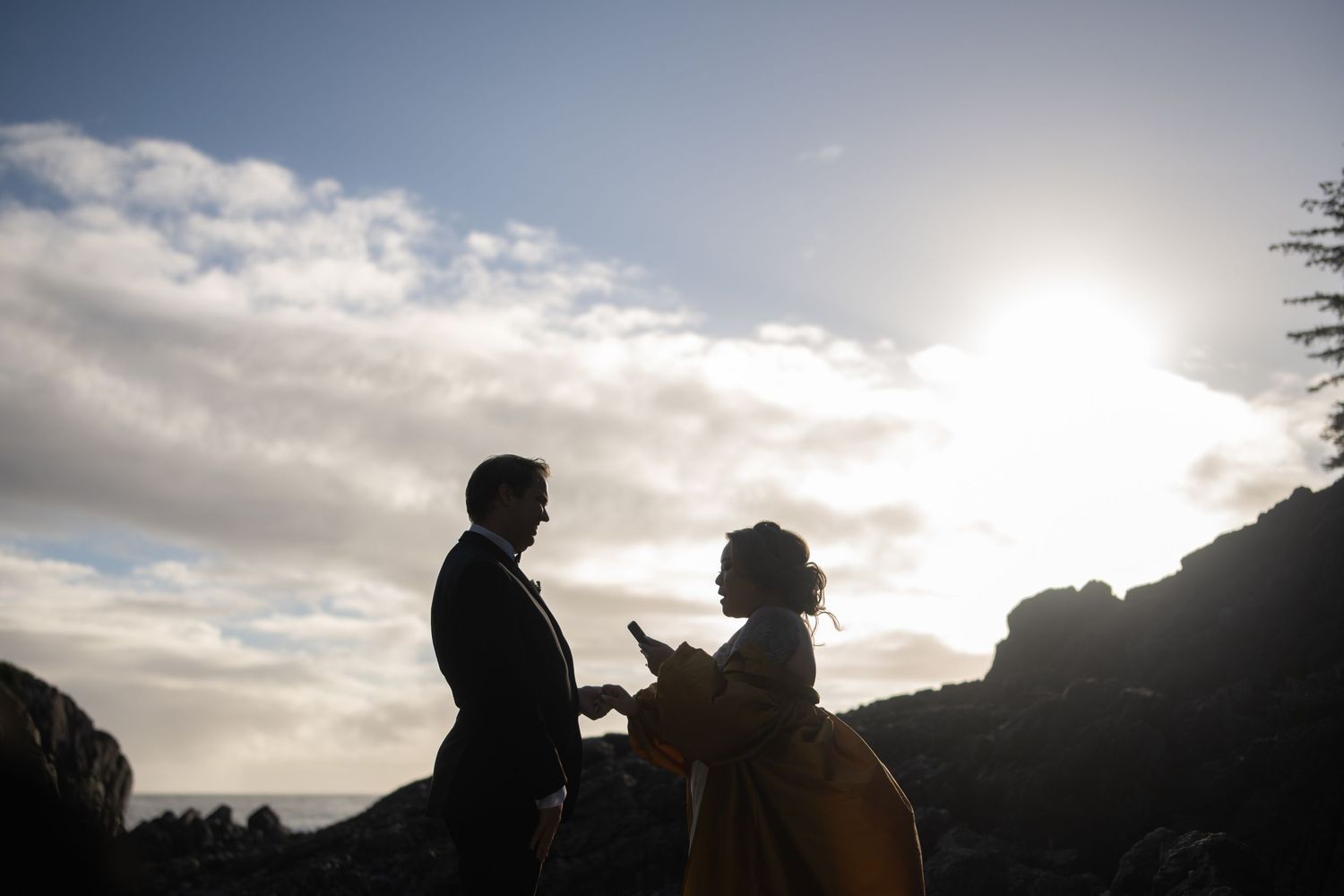 Silhouettes against a cloudy sunset sky along a dramatic coastline.