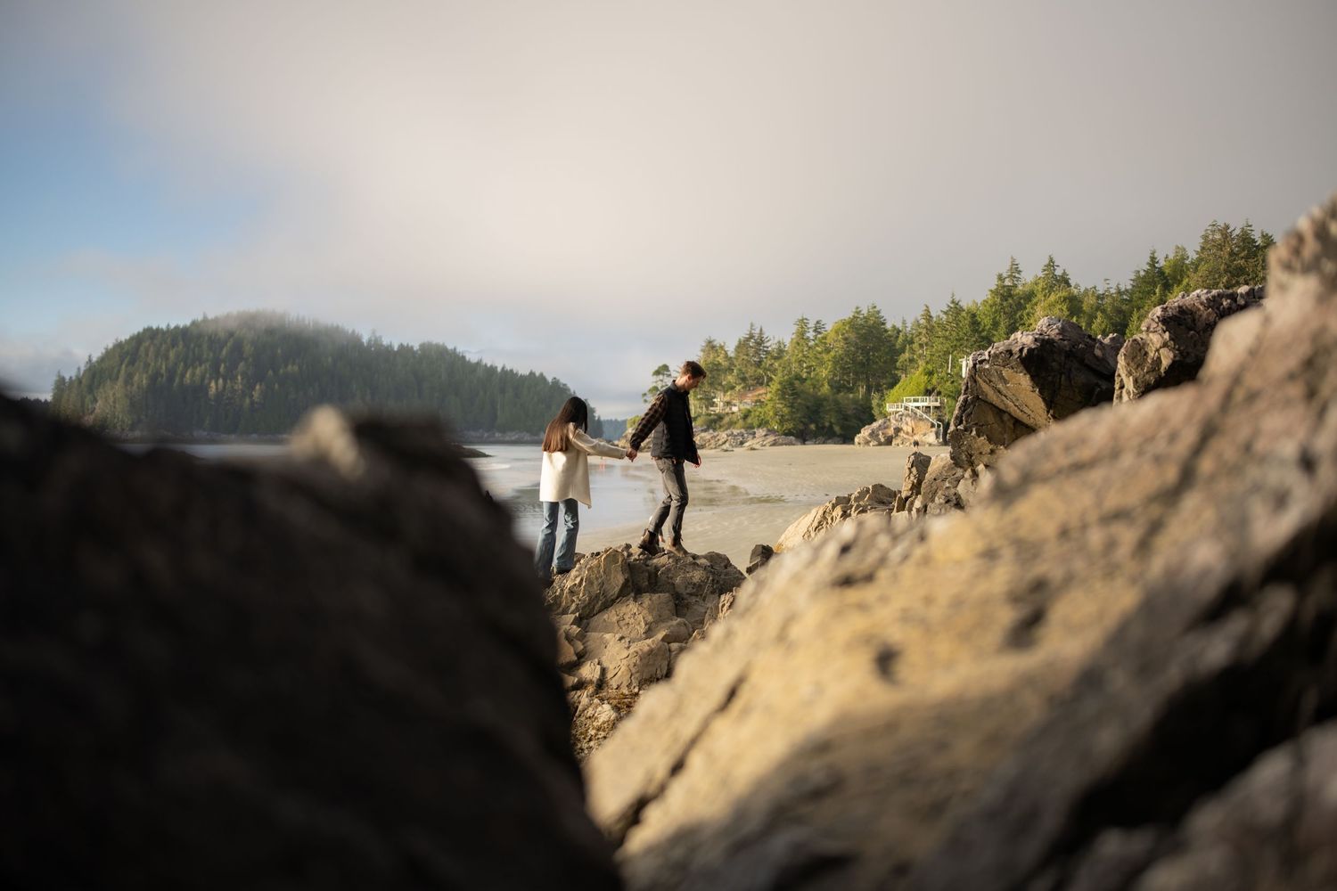 Low-angle view of beach rocks and sand with distant coastline.