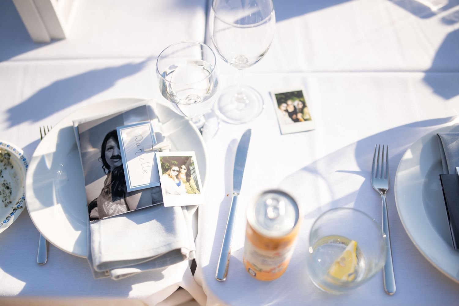Wedding table setting with wine glasses, place settings and decorative details in natural sunlight.