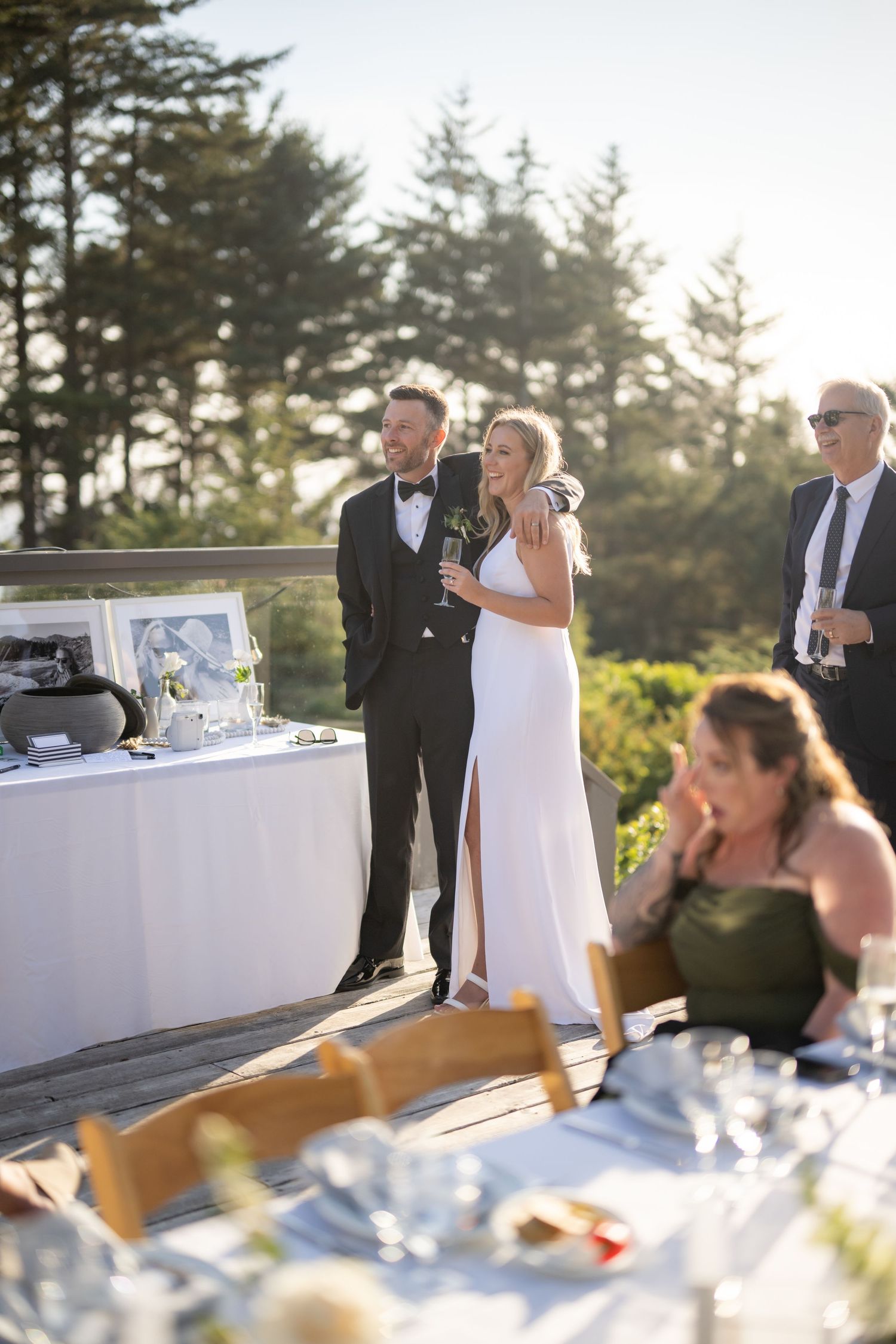 Elegant outdoor wedding reception setup with tables and evergreen trees in the background.