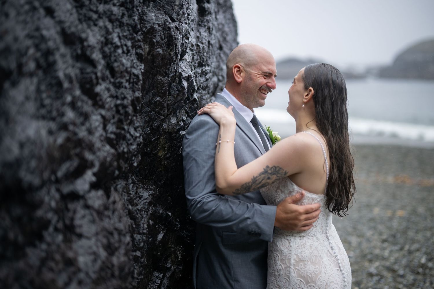 A tender moment shared against a wet rocky backdrop on a moody Pacific Northwest beach.