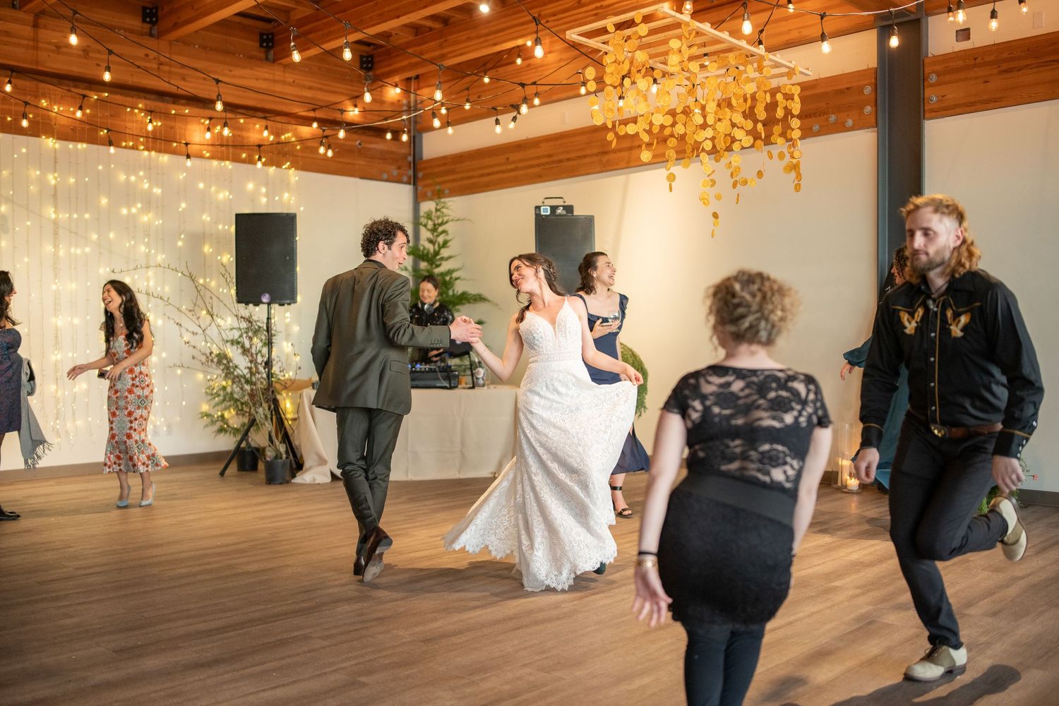Wedding celebration in a rustic venue with wooden pillars and string lights creating a warm atmosphere.