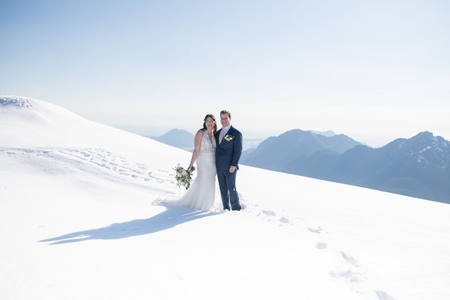 Winter wedding photo session on a snow-covered mountain summit.