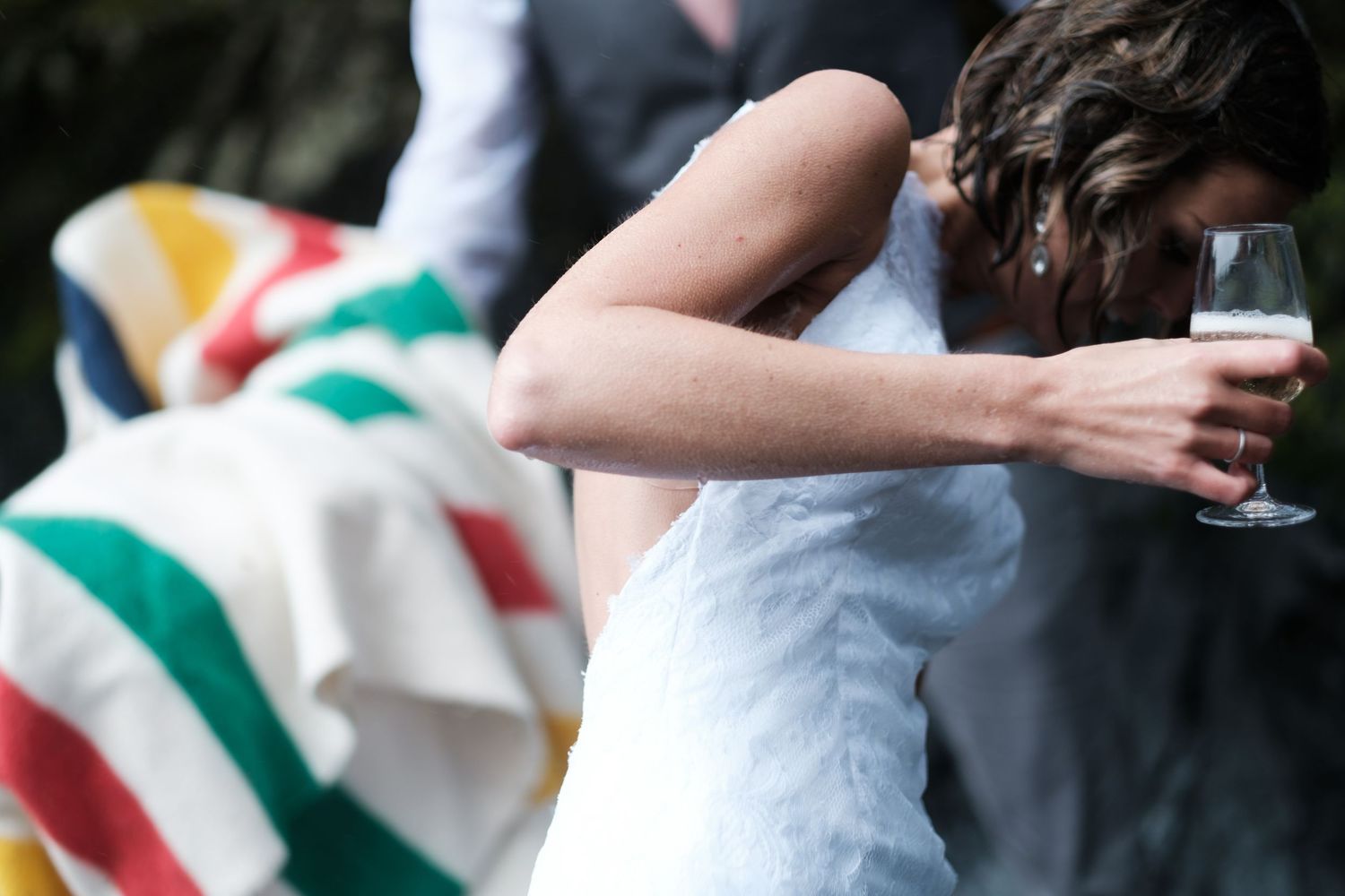 Couple wrapped in striped blanket during outdoor celebration.