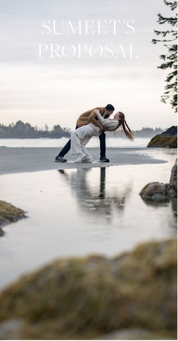 A romantic couple embraces in a dramatic dip pose on a misty beach at sunset, creating a reflection in shallow water.