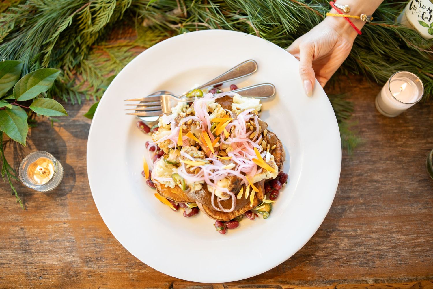 Plates of artfully plated pasta dishes being served on a rustic wooden table.