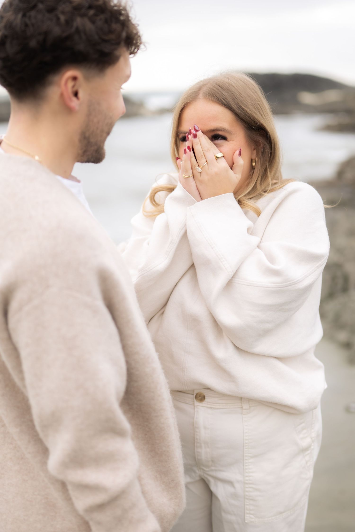Emotional moment captured between two people in cream colored sweaters on a beach.