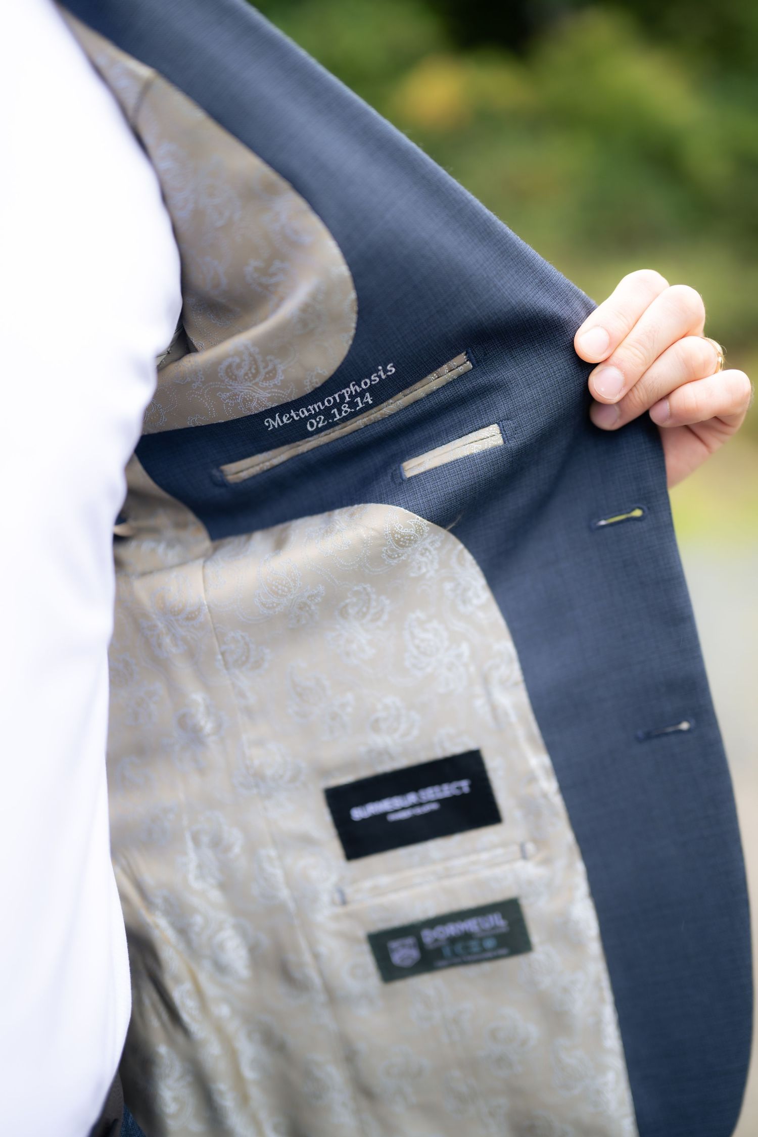 Close-up details of a navy blue suit jacket showing the inner lining and labels.