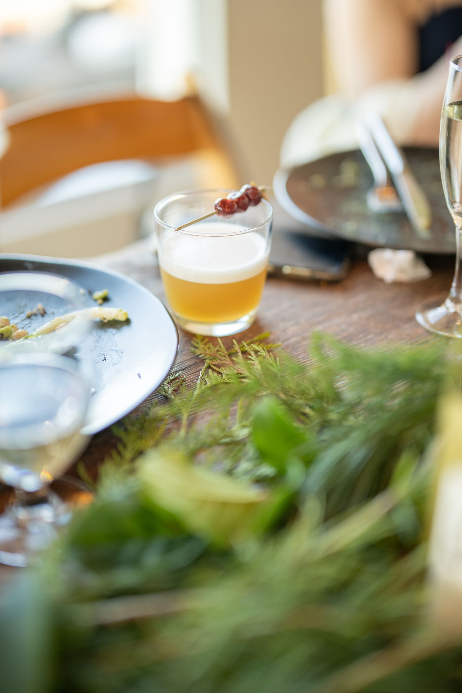Close up of craft beer in glass with blurred dining plates in background.