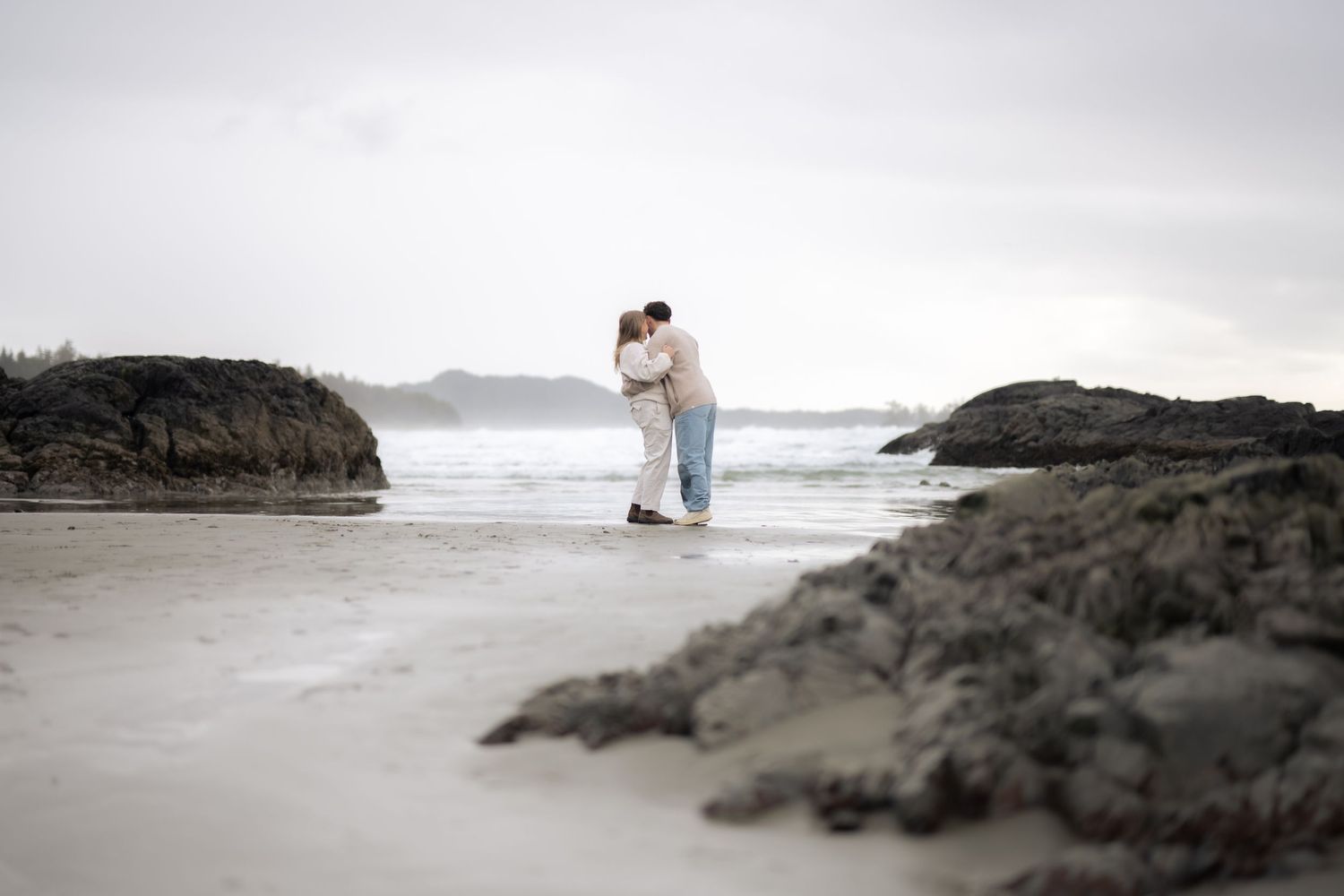 Atmospheric beach engagement scene with rocky formations and misty ocean backdrop.