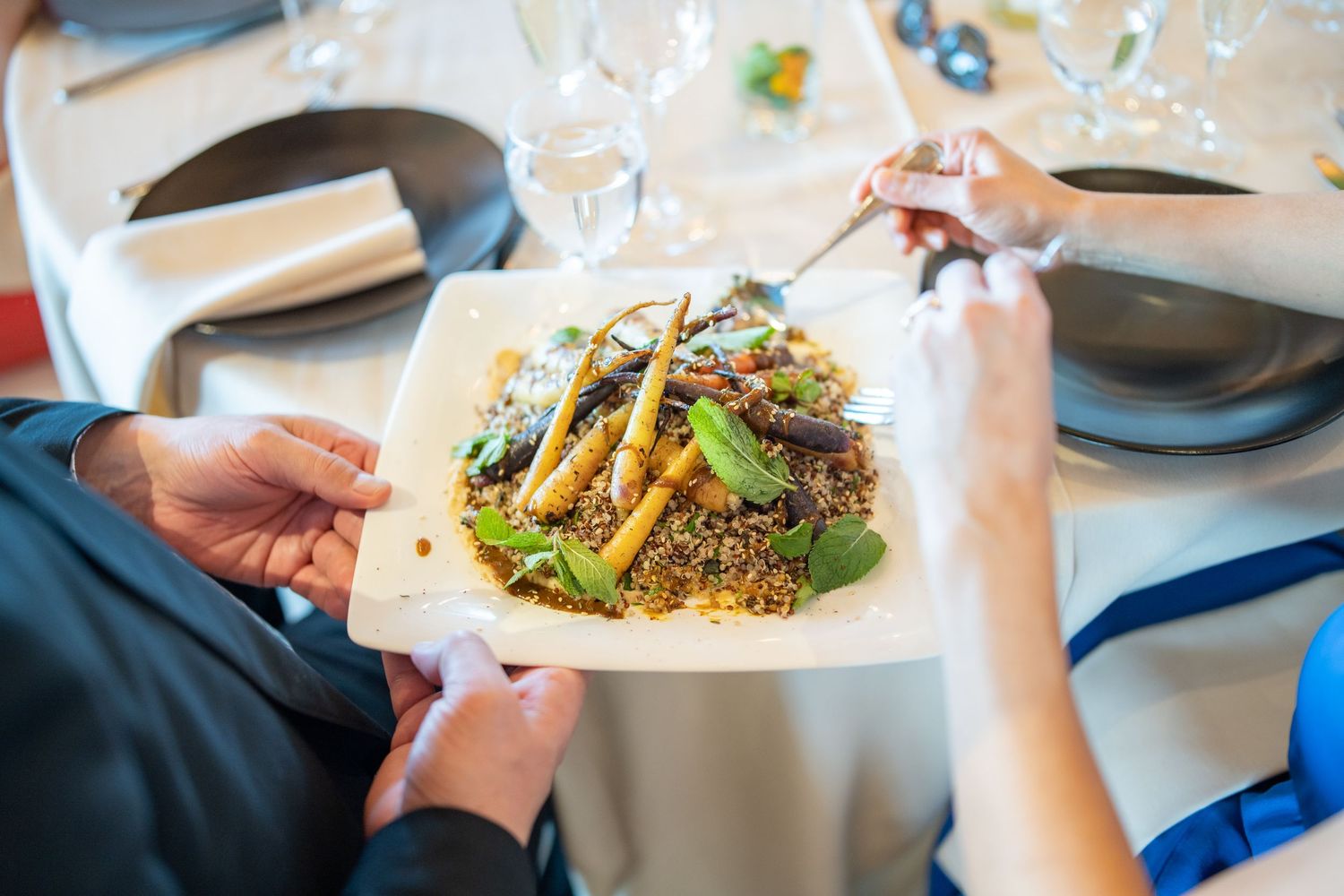 Elegant plated dish with fresh greens and garnishes being served at upscale restaurant.