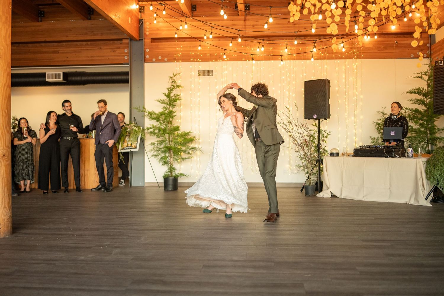 Wedding reception hall with wooden beams and string lights creating romantic atmosphere.