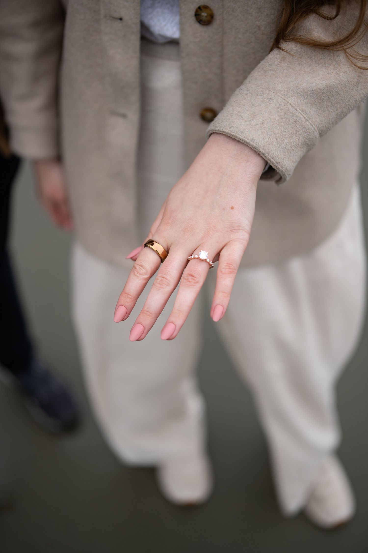 Close-up shot of hands wearing elegant wedding rings against a light-colored background.