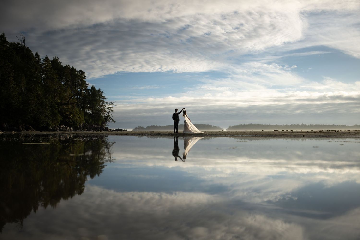 Panoramic view of a serene lake reflecting dramatic clouds in the sky.