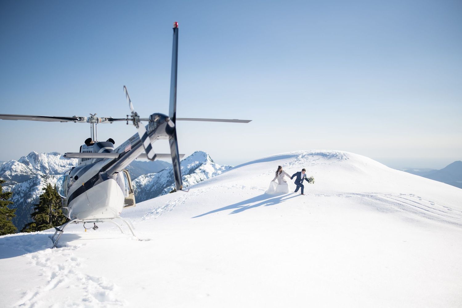 Scenic mountain helicopter tour with snow-covered peaks and clear blue skies.
