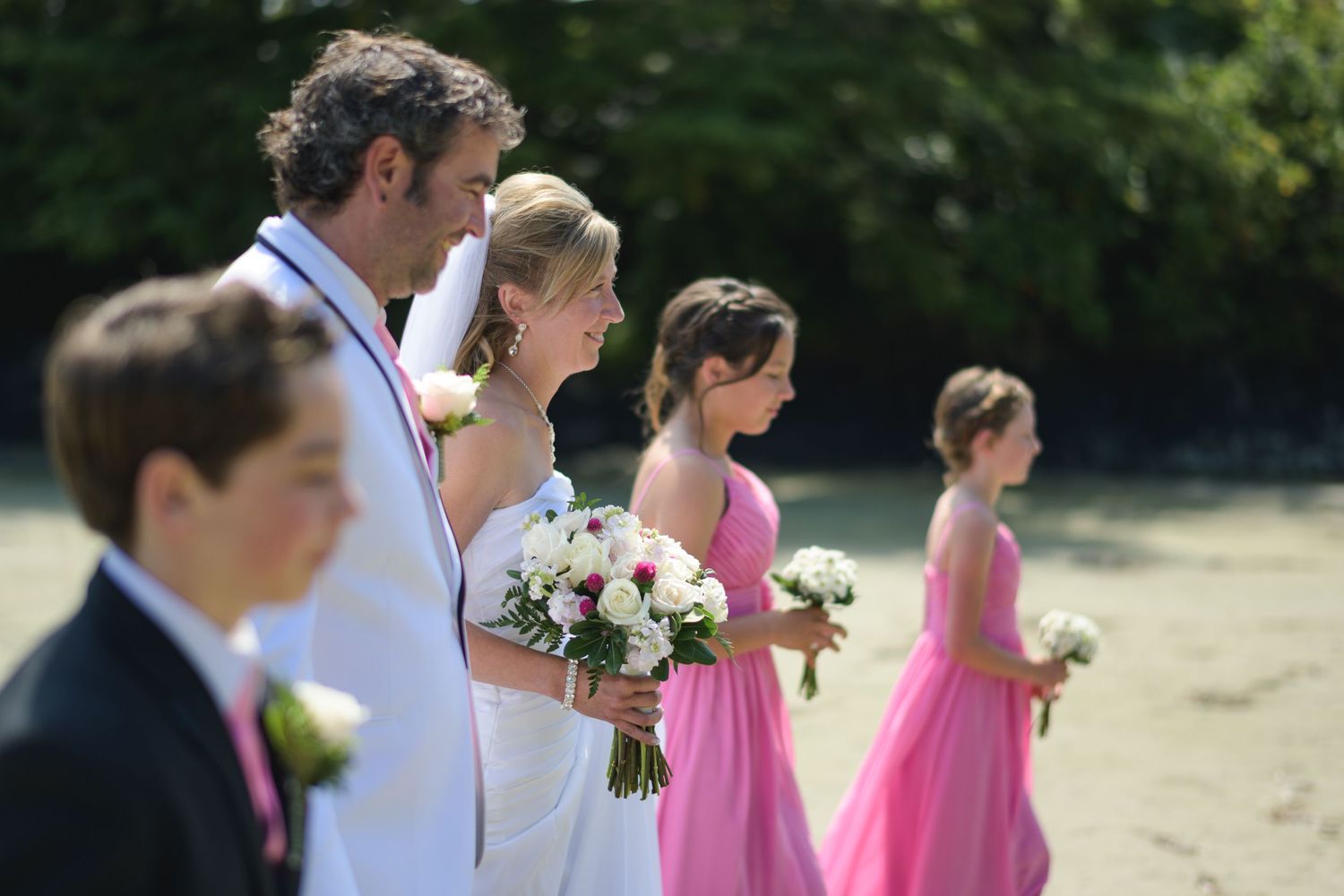 Outdoor wedding ceremony with pink bridesmaid dresses and natural setting.