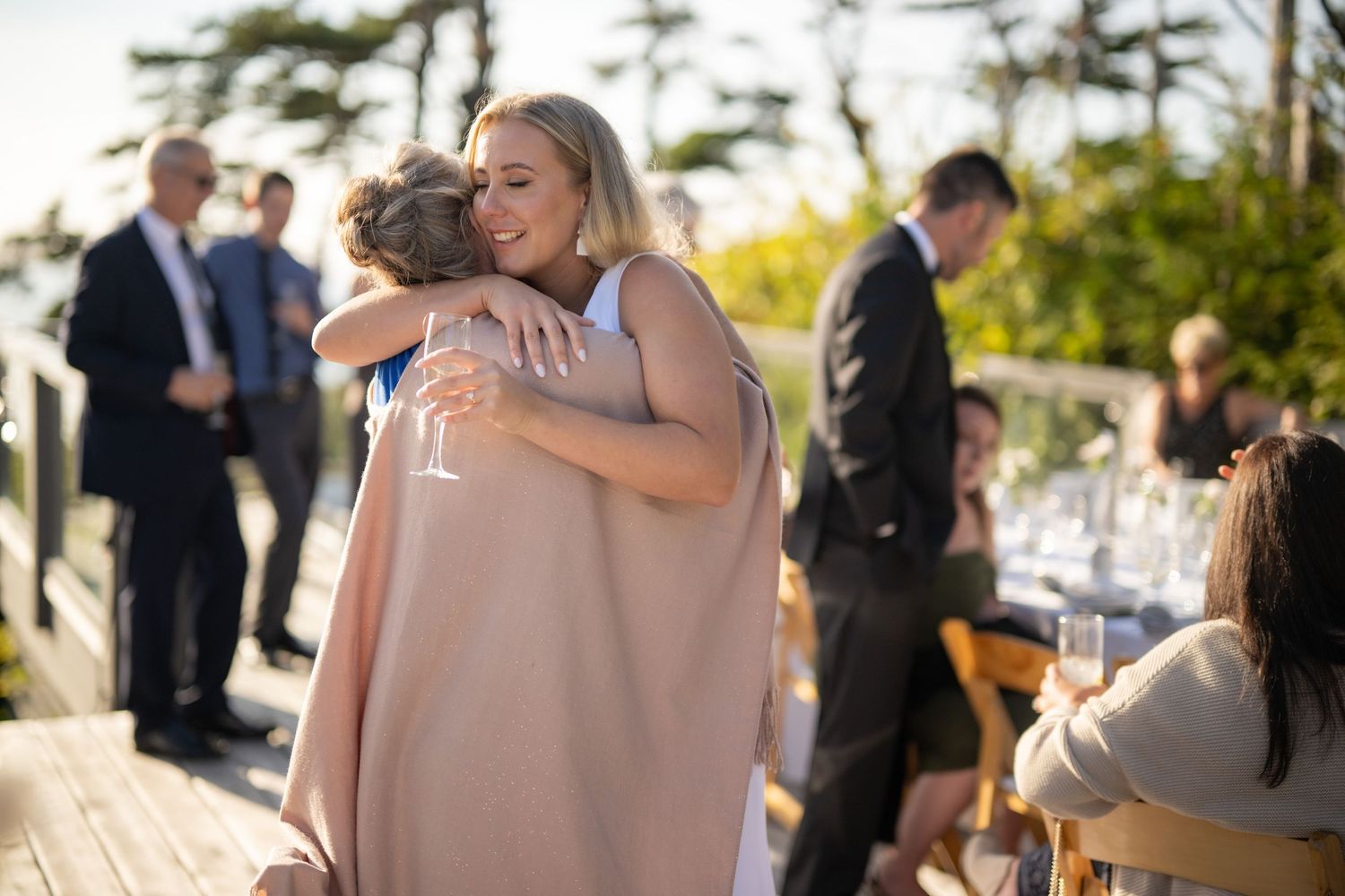 Heartfelt embraces shared between guests at an outdoor wedding celebration.