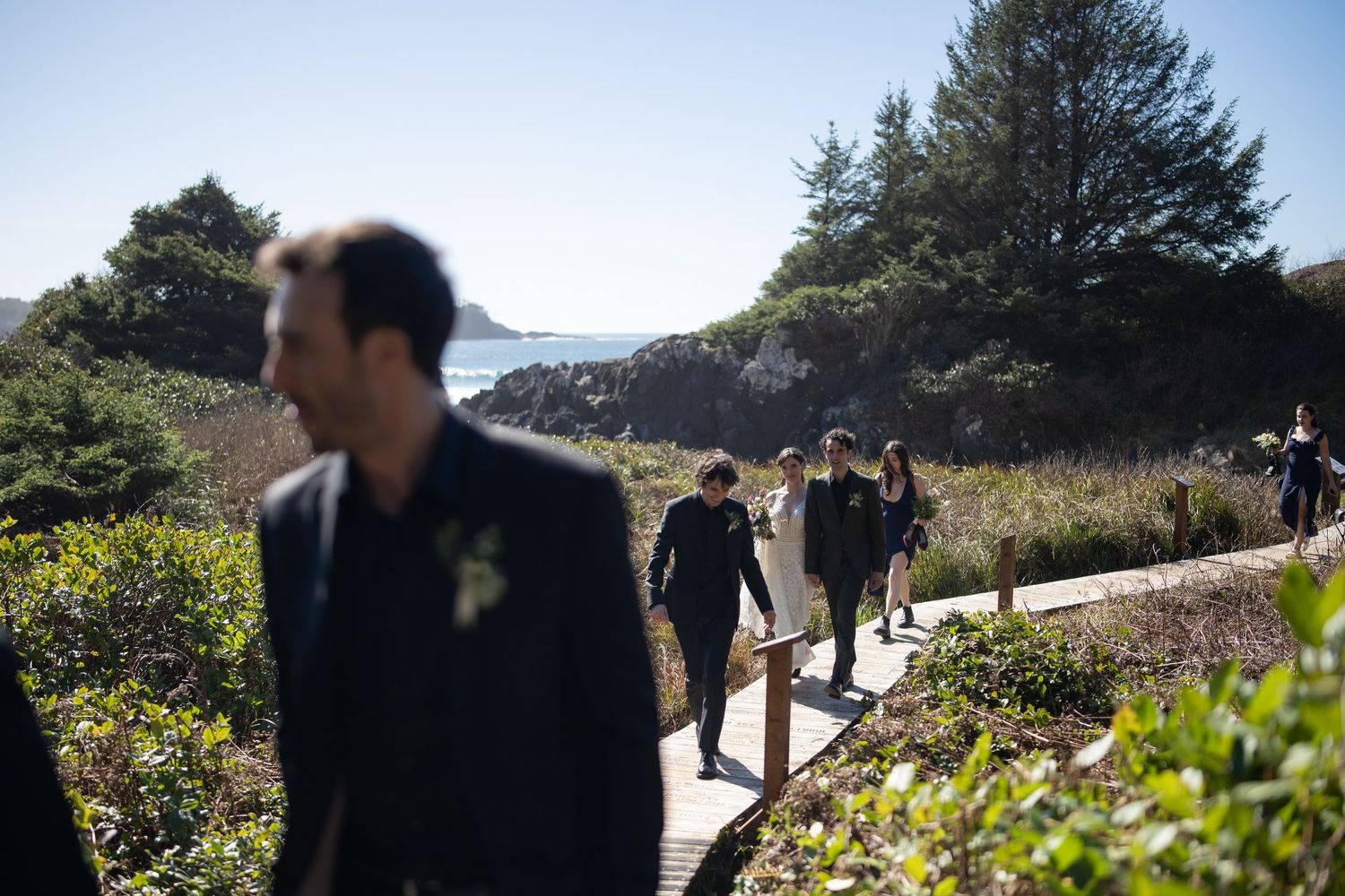 People exploring scenic coastal trail with wildflowers and ocean vistas.