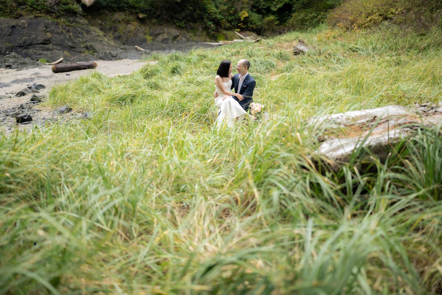 Distant view of couple through tall grass on coastal cliffside.
