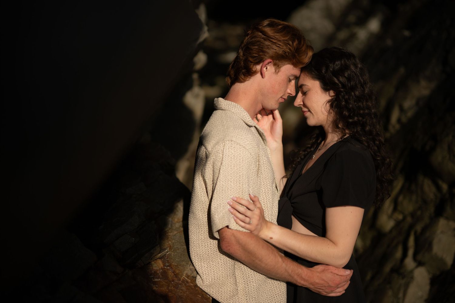 Intimate silhouettes against dark rocky backdrop near the coastline.