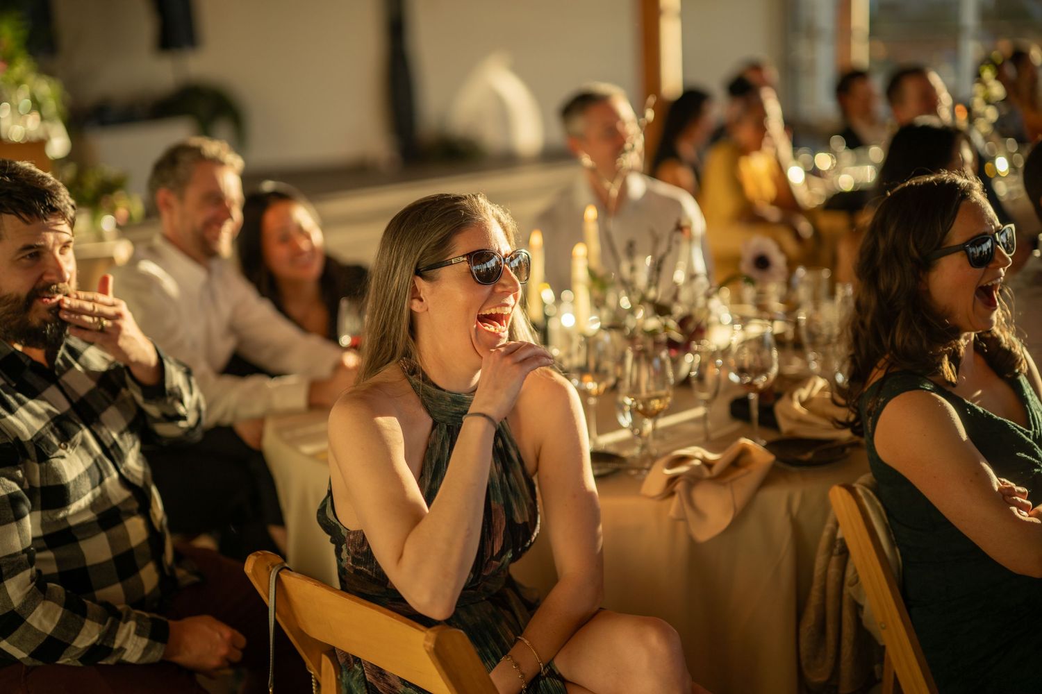 Guests enjoying a lively celebration at a waterfront venue with golden hour lighting.