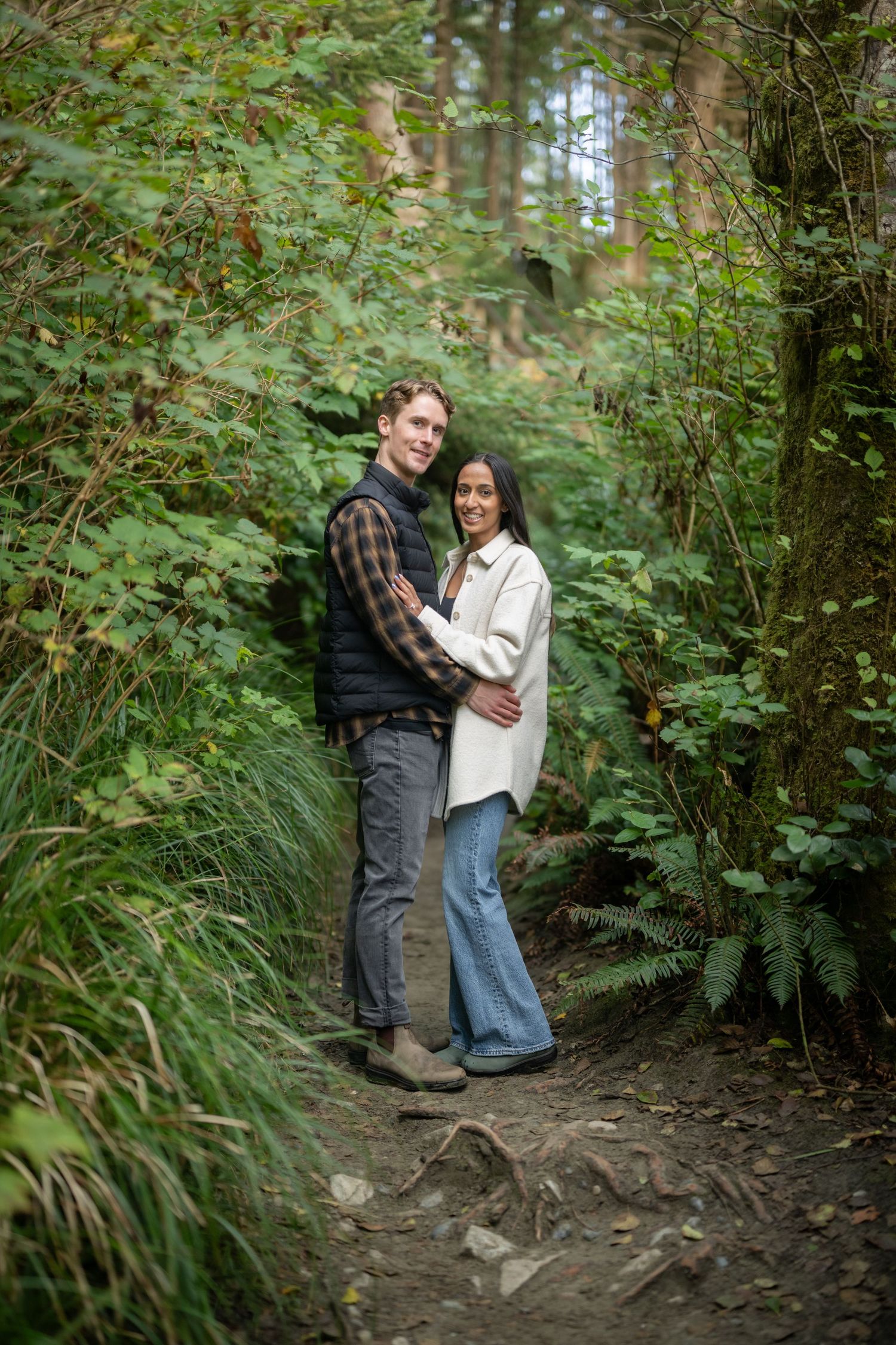 Forest path surrounded by lush green vegetation and tall trees.