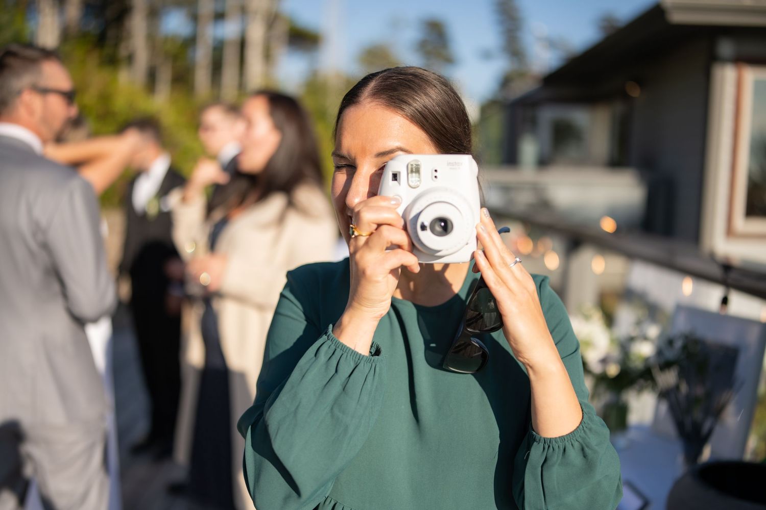 Guest takes photo with instant camera during outdoor wedding reception.