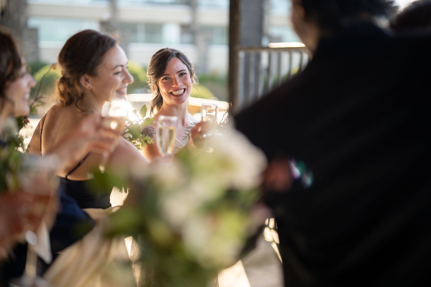 Guests enjoying drinks and conversation during sunset at an outdoor wedding reception.