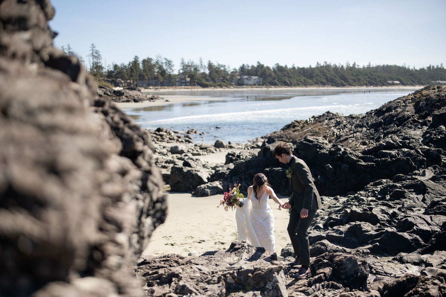 A wedding ceremony taking place among dramatic rocky coastal formations and beach scenery.