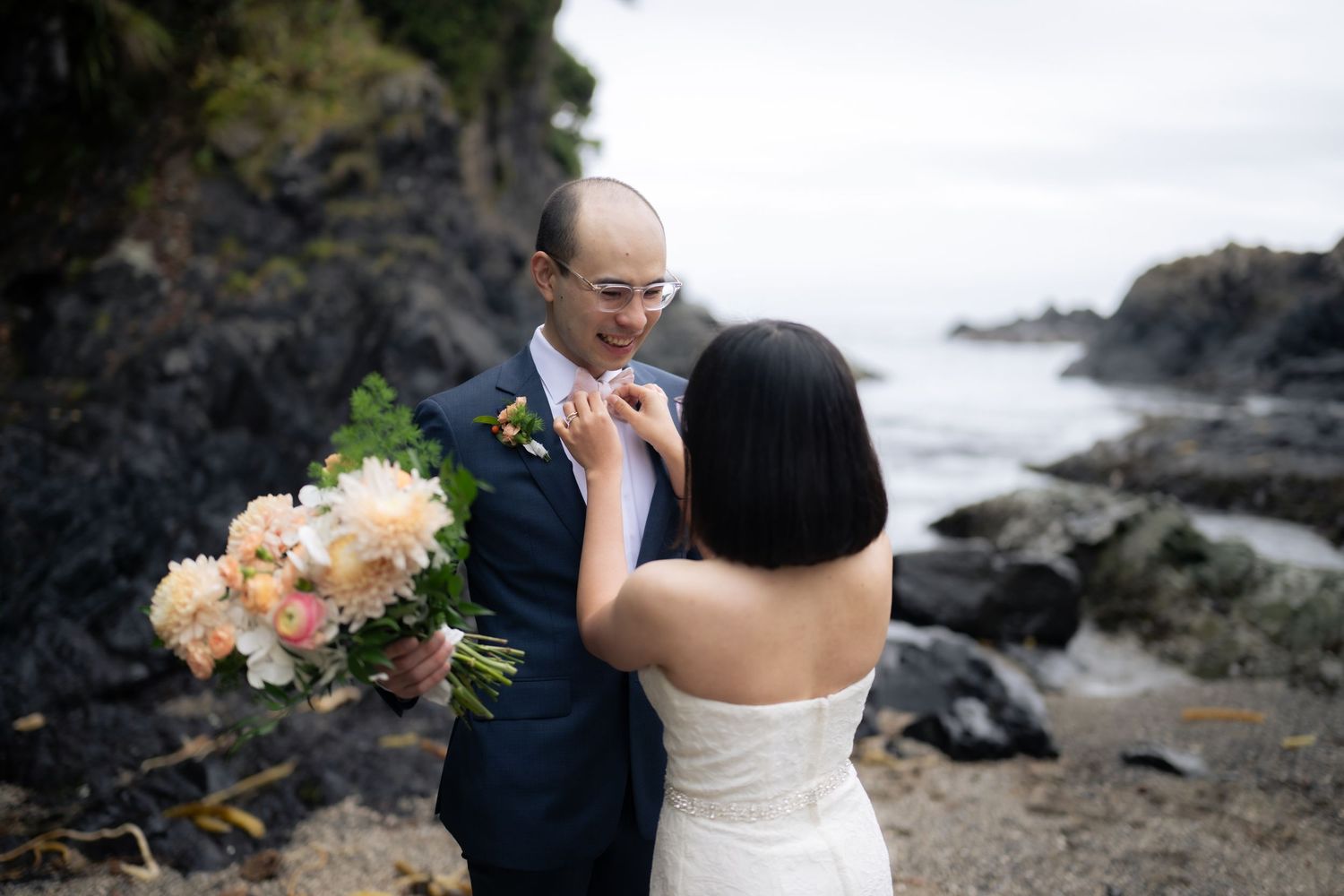 Romantic wedding ceremony taking place on a dramatic rocky coastline with ocean views.