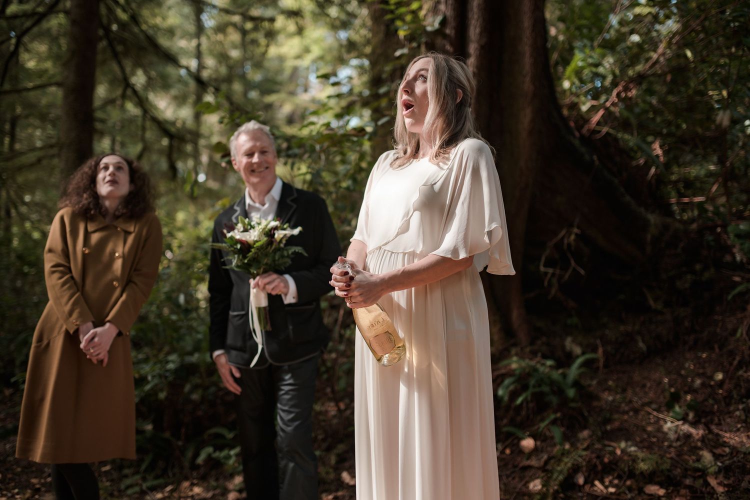 A wedding ceremony takes place in a lush forest setting.