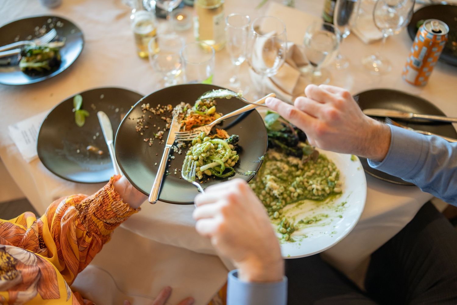 Diners sharing family-style plates of food across an elegant table setting.
