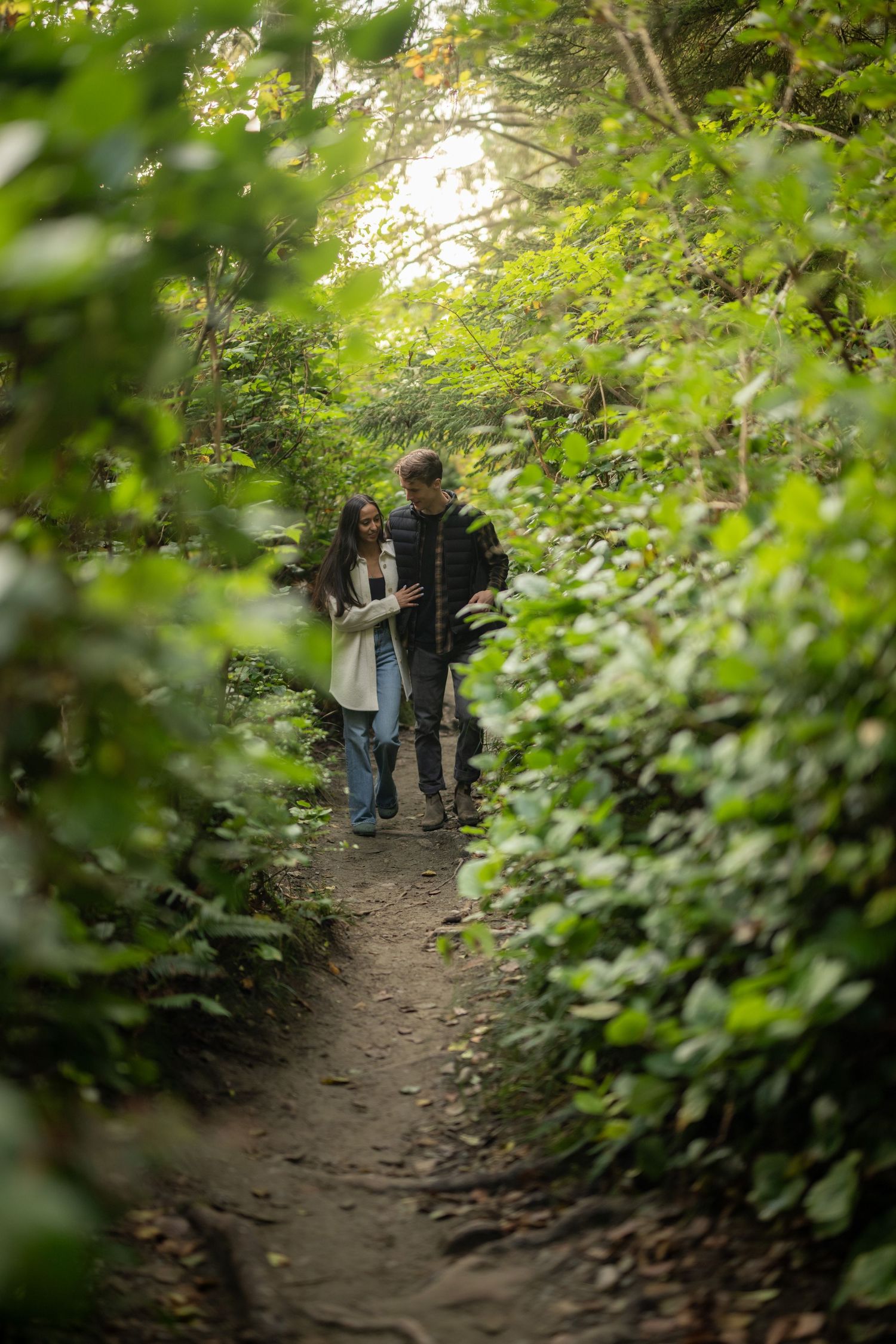 Forest path lined with lush green foliage and filtered sunlight creating a romantic atmosphere.