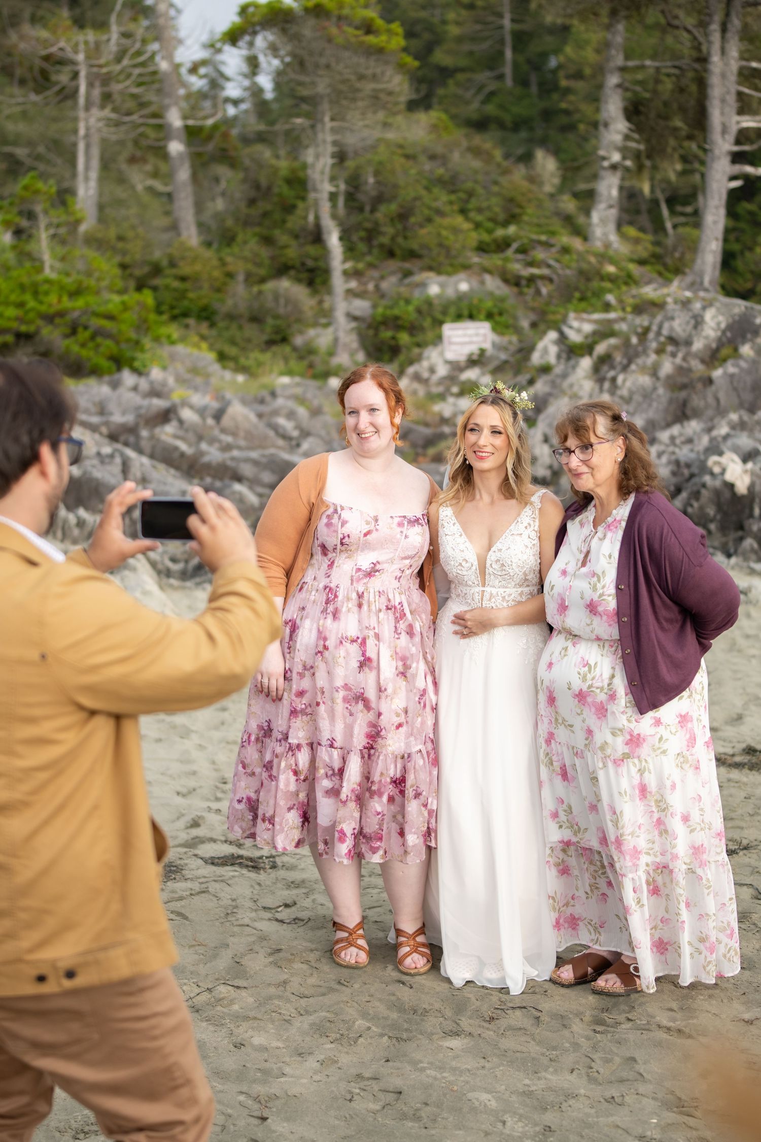 Group poses for photos against rocky coastal backdrop with evergreen trees.