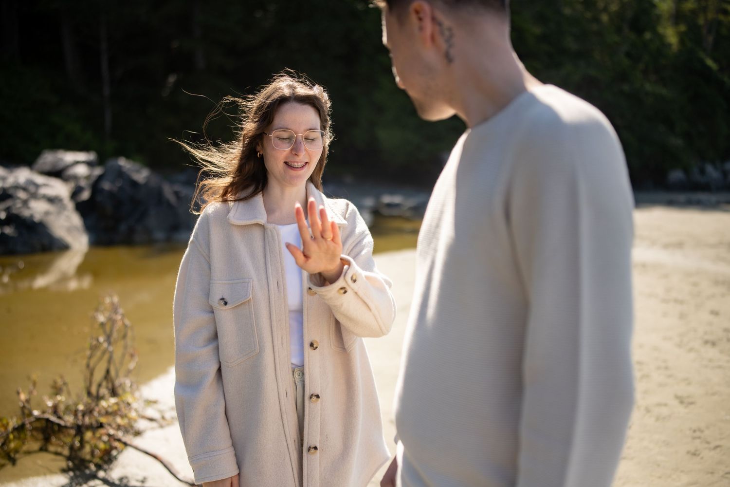 A couple in light colored outfits share a romantic moment on a sunny beach.