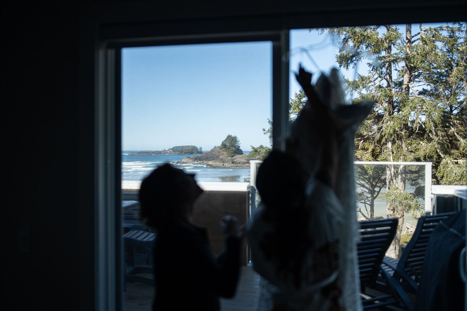 Ocean view through a window with trees visible in the distance.