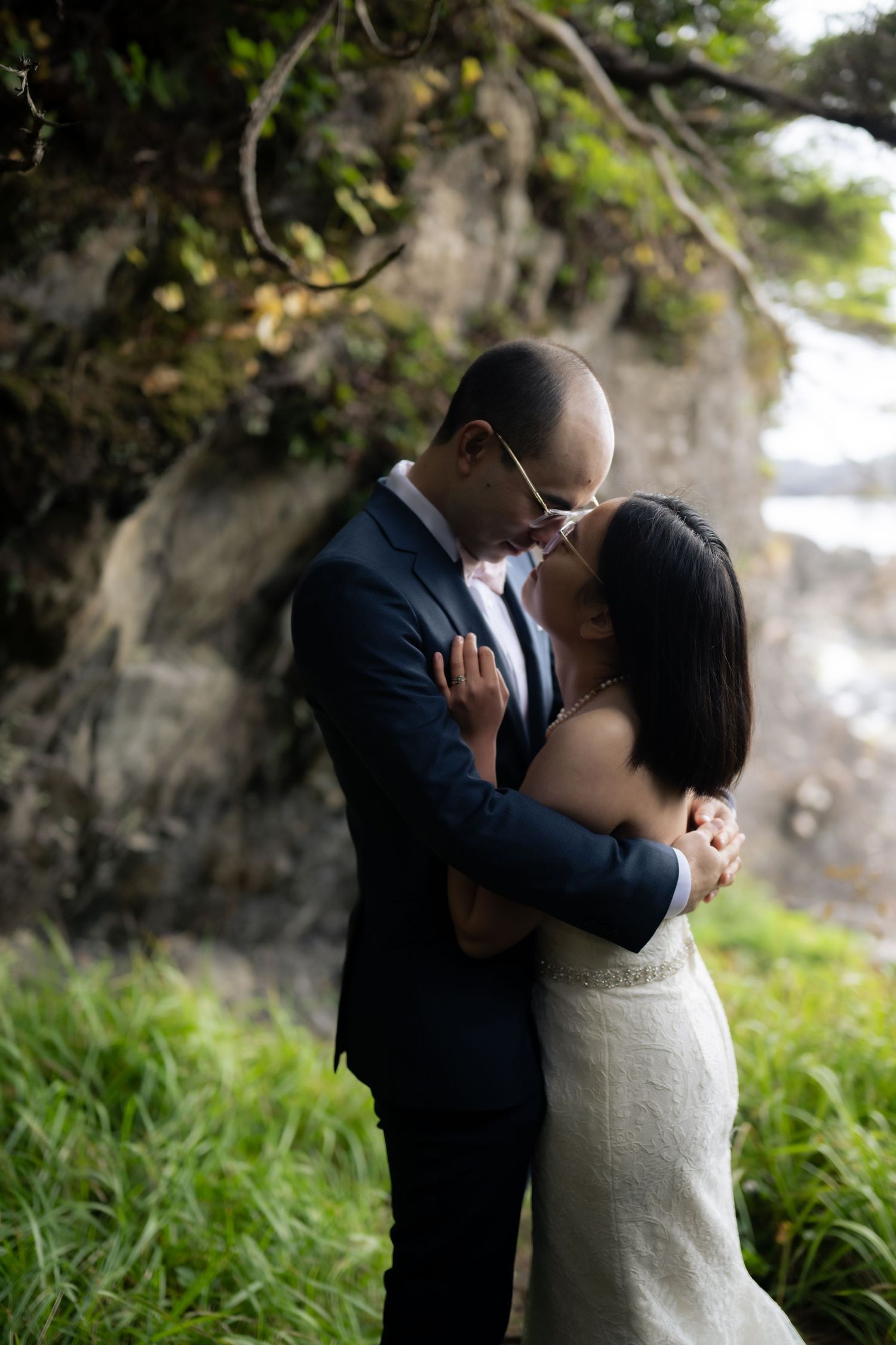 A romantic wedding couple shares intimate moments against a natural outdoor backdrop.