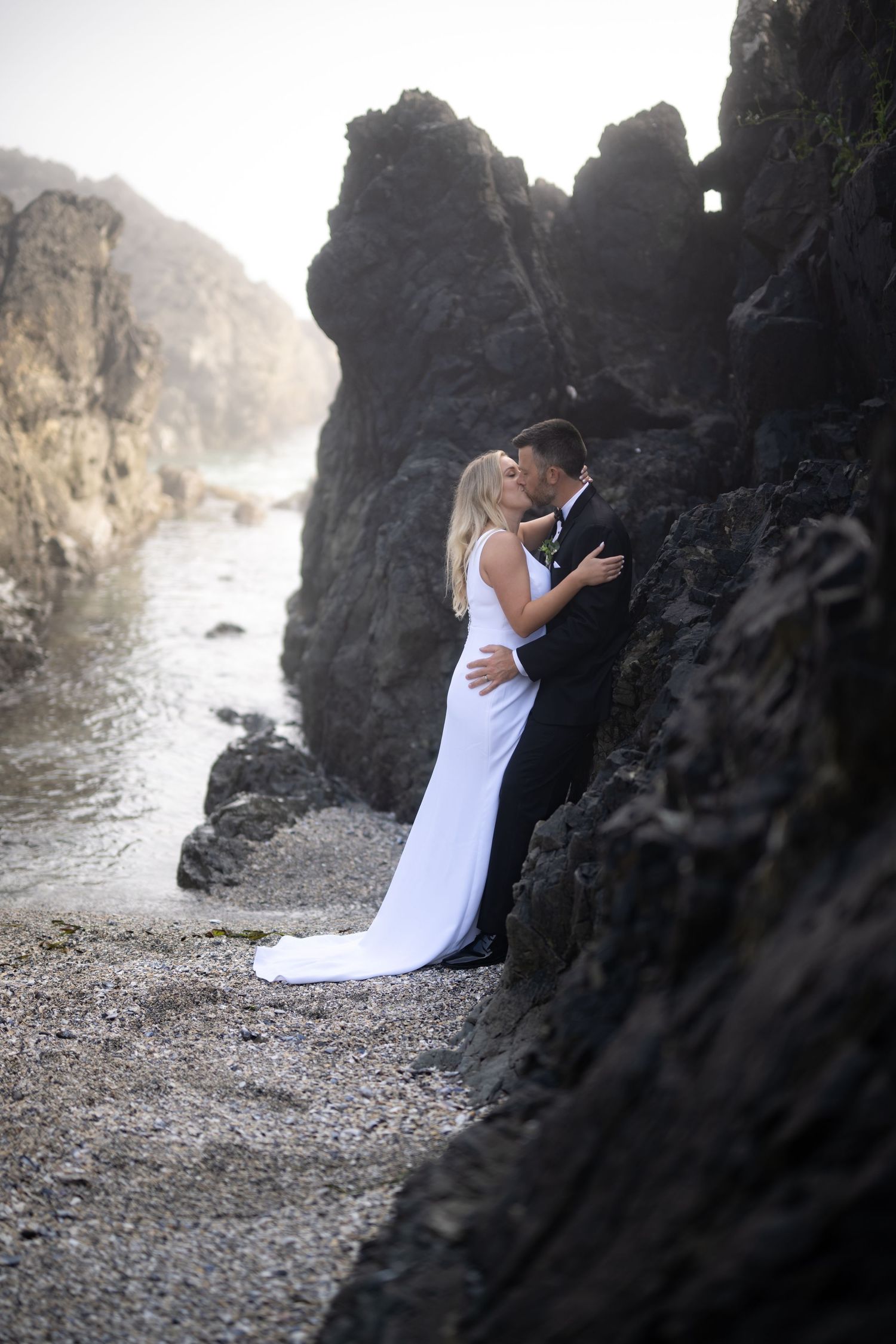 Romantic wedding portraits captured between dramatic coastal rock formations.
