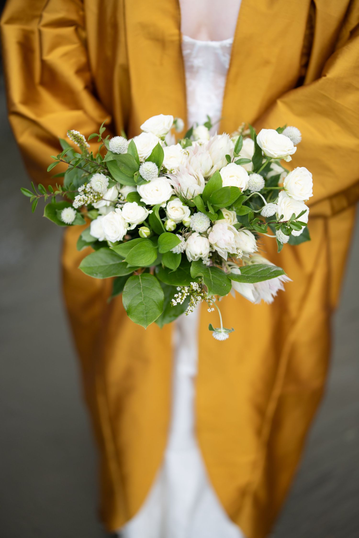 A delicate white floral bouquet against a mustard yellow background.