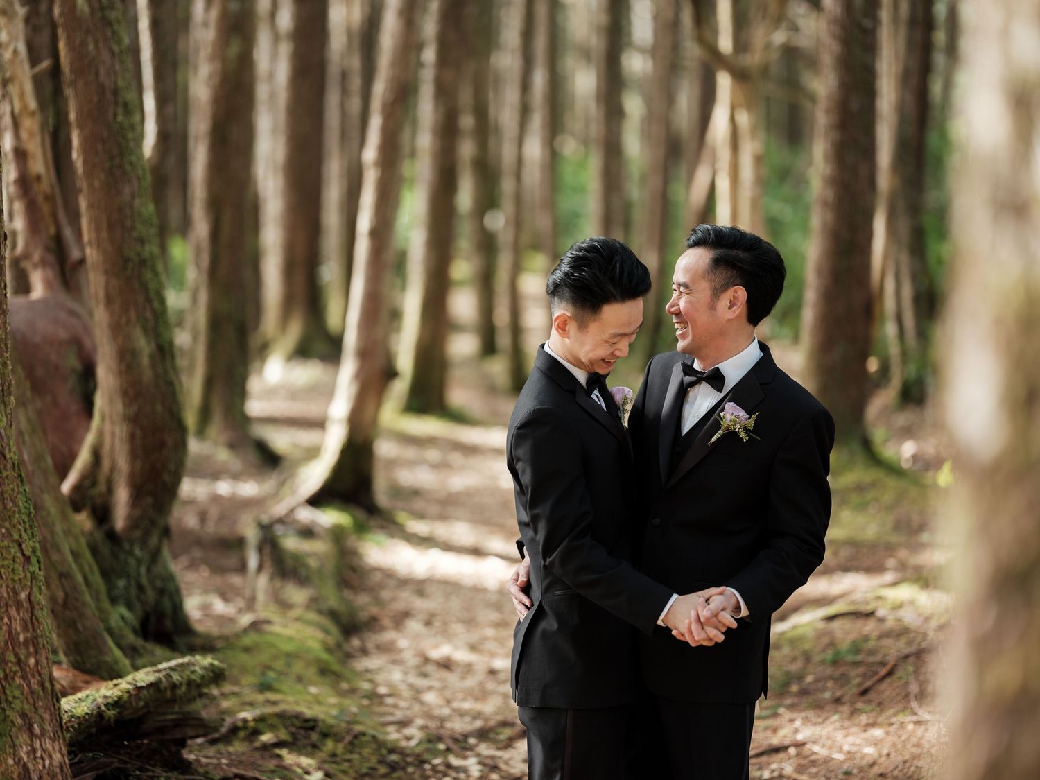 Couple sharing a tender moment among tall trees in a forest wedding setting.