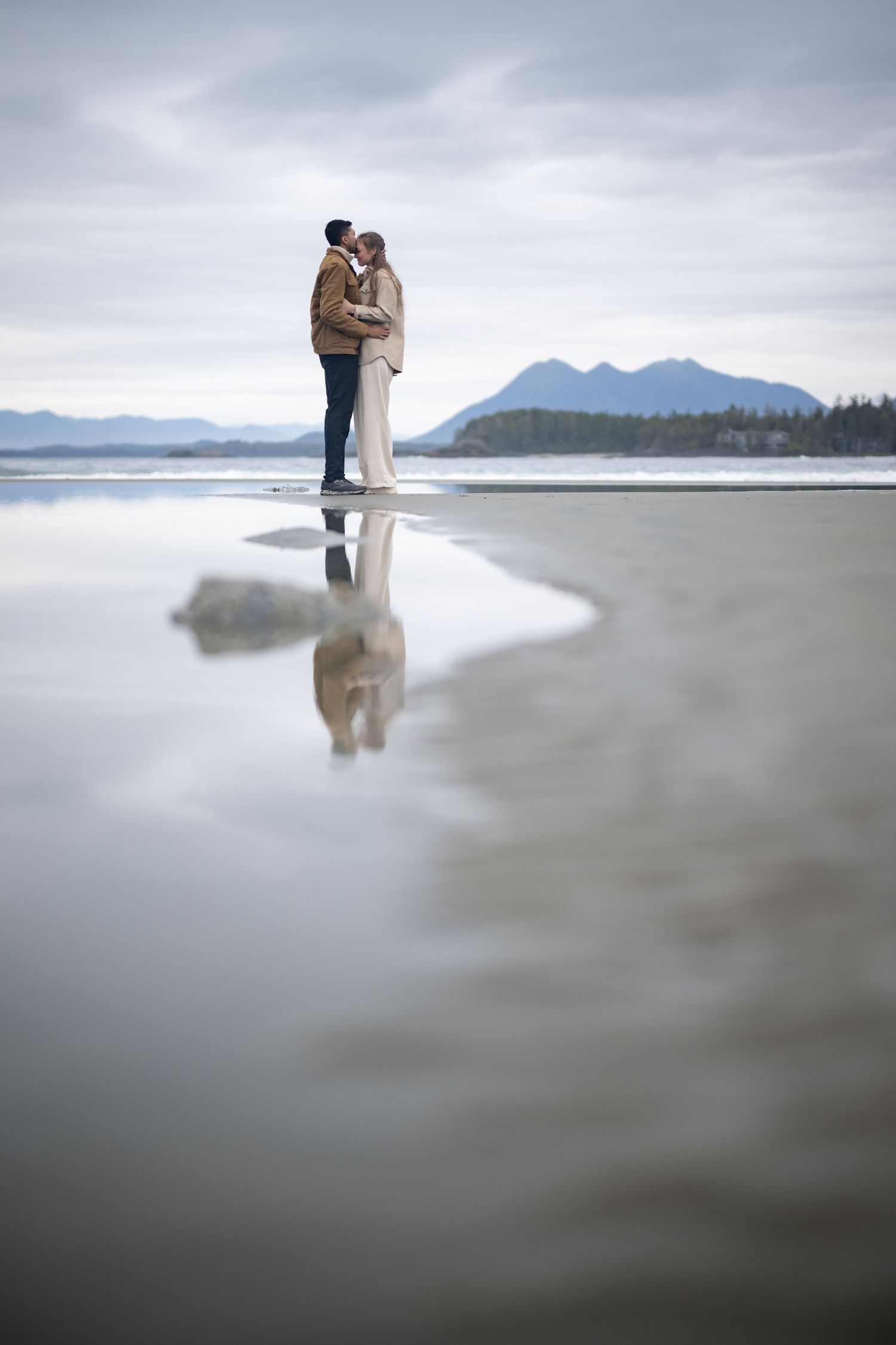 Artistic beach portraits with misty water reflections and mountain silhouettes.