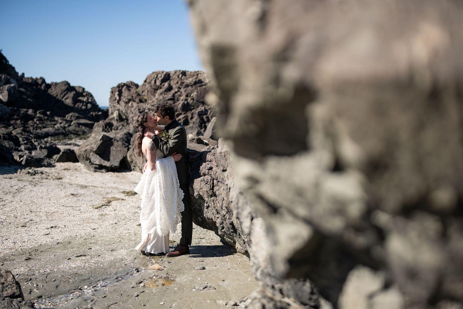 Intimate wedding ceremony setting among coastal rock formations with ocean backdrop.