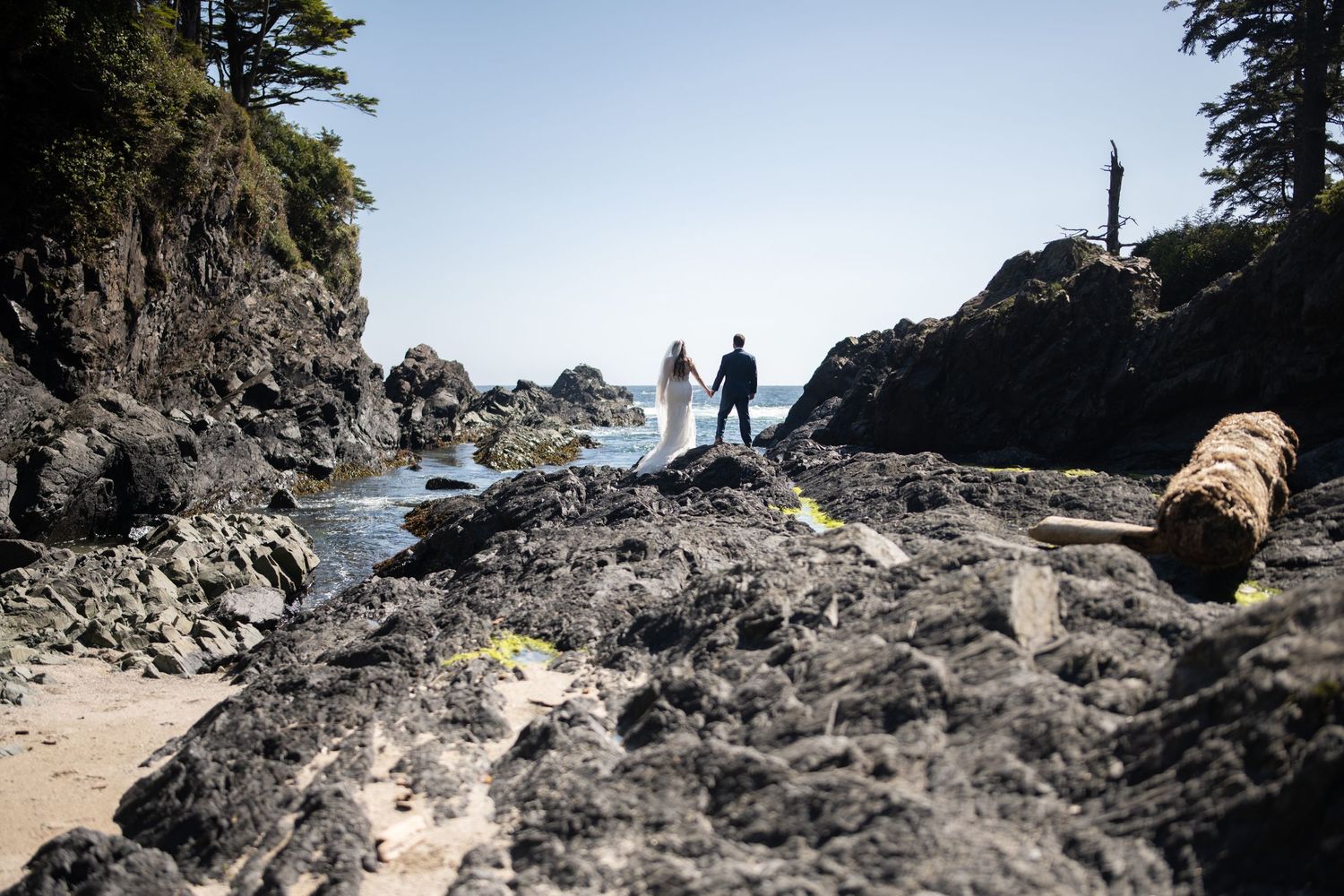 Rocky coastal landscape with silhouettes visible against bright sky.