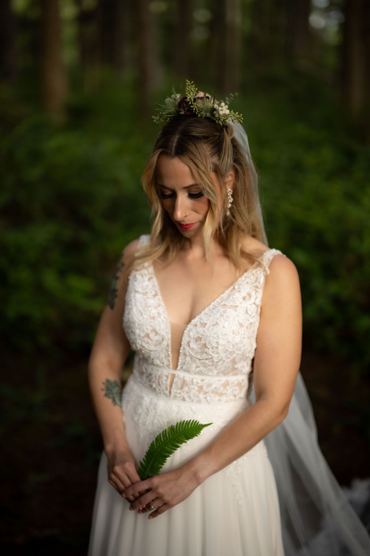 Close-up details of lace wedding dress bodice with plunging neckline in forest setting.