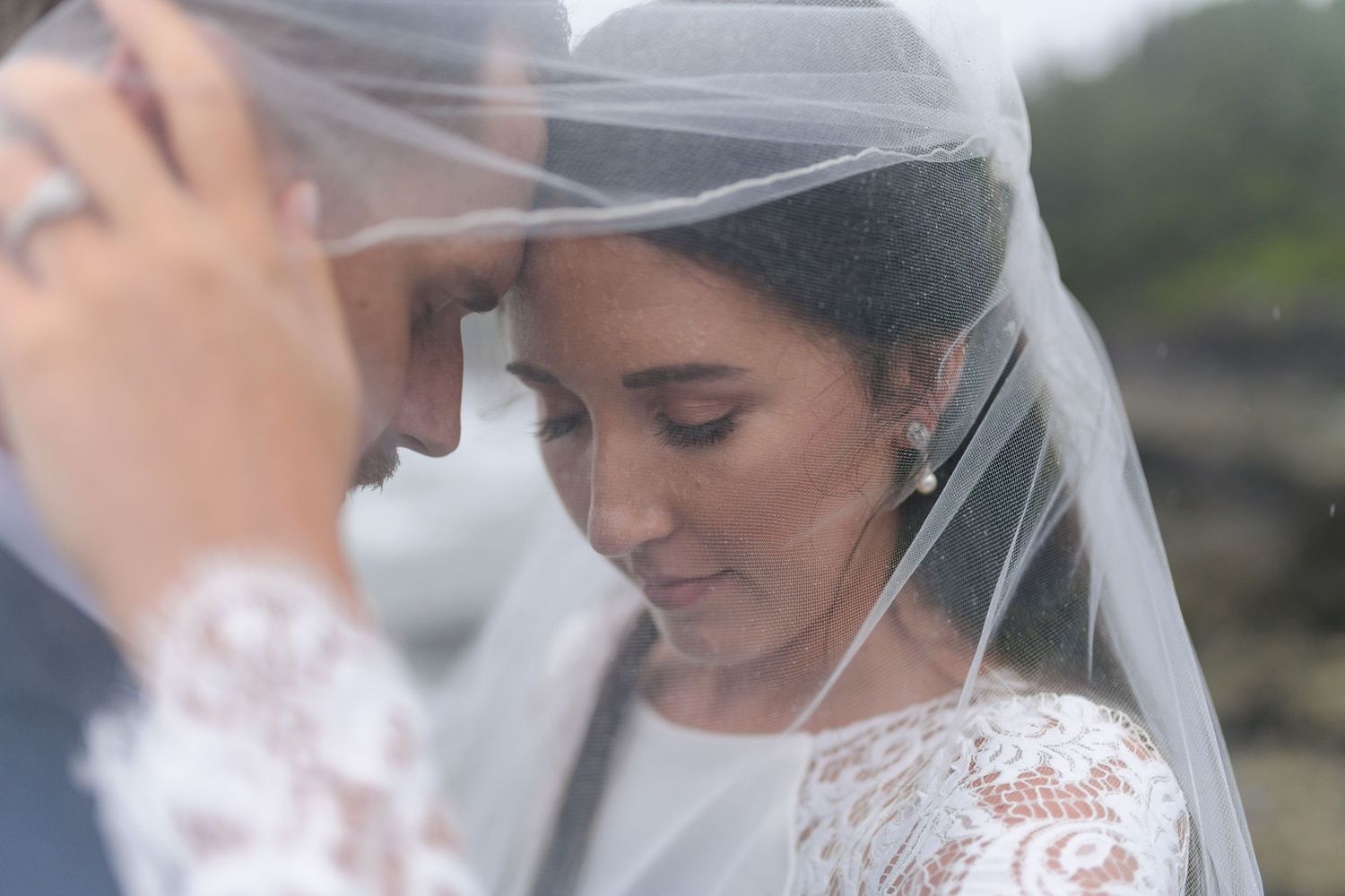 Intimate wedding moment captured through a flowing white veil.
