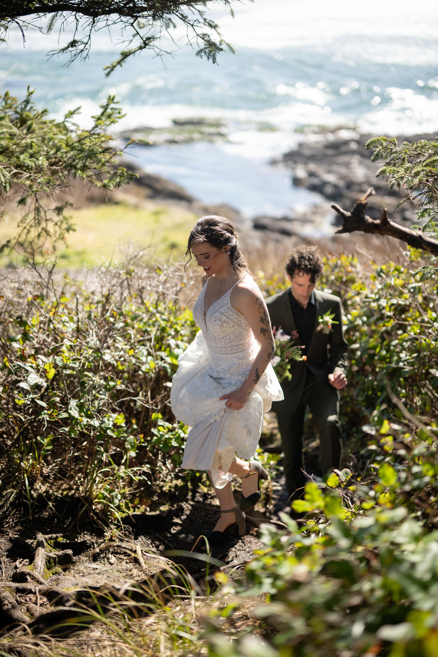Couple walking through blooming wildflowers along rocky Pacific Northwest coastline.