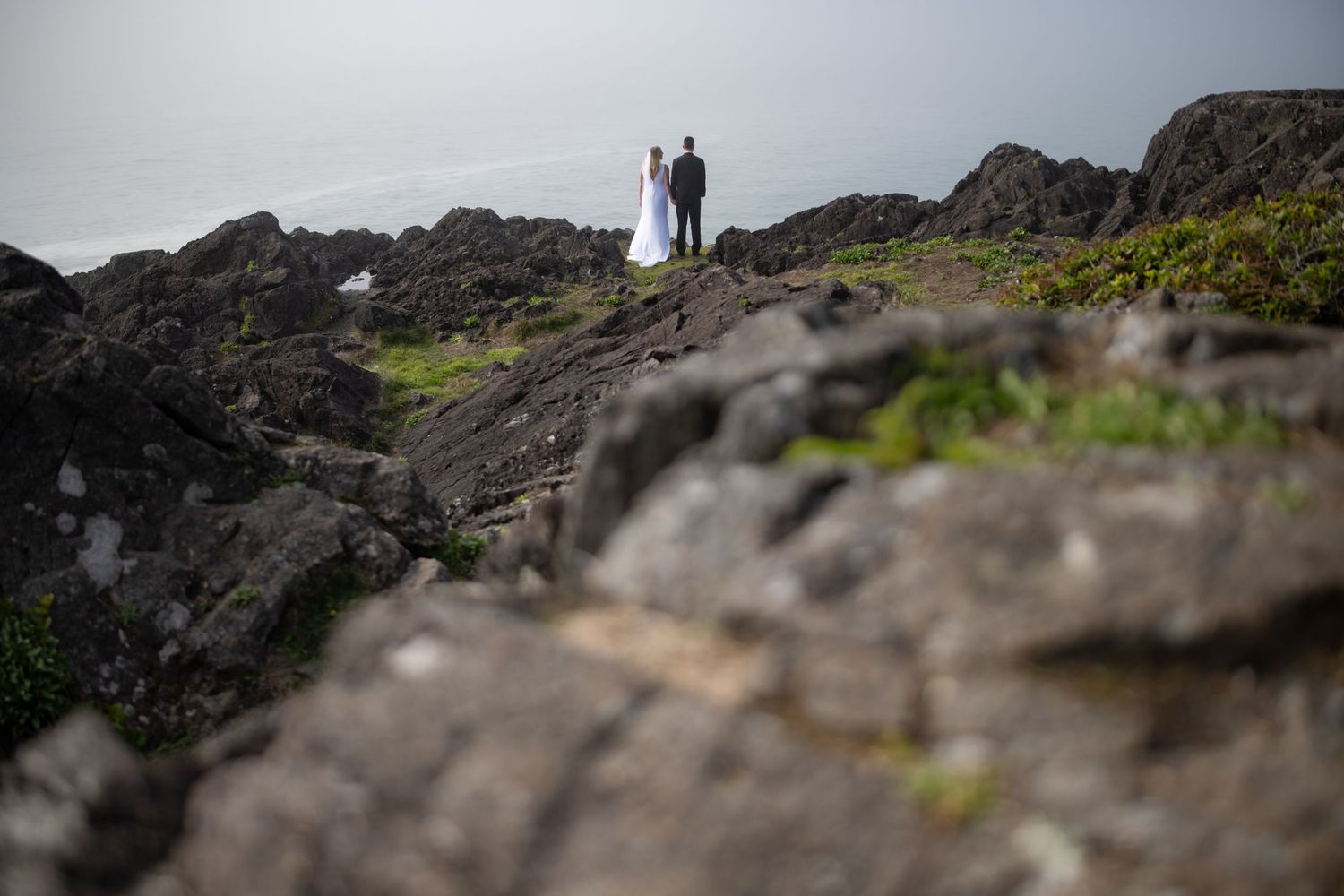 Two silhouettes standing on a dramatic rocky cliff overlooking misty scenery.