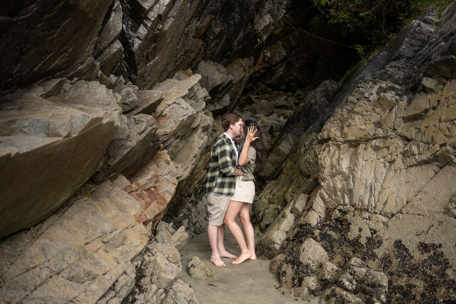 A romantic moment between two people embracing against a rocky cliff face.